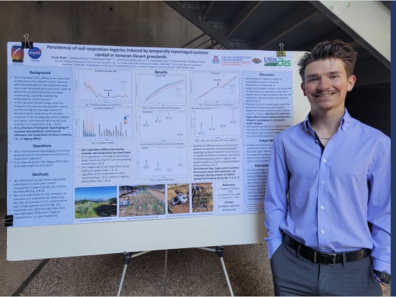 Jacob Blais standing next to poster.