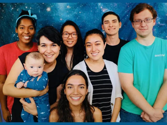 Cathryn Sephus, top left, and Betul Kacar, second from left, pose with members of the Kacar Lab. Betul Kacar holds her child.