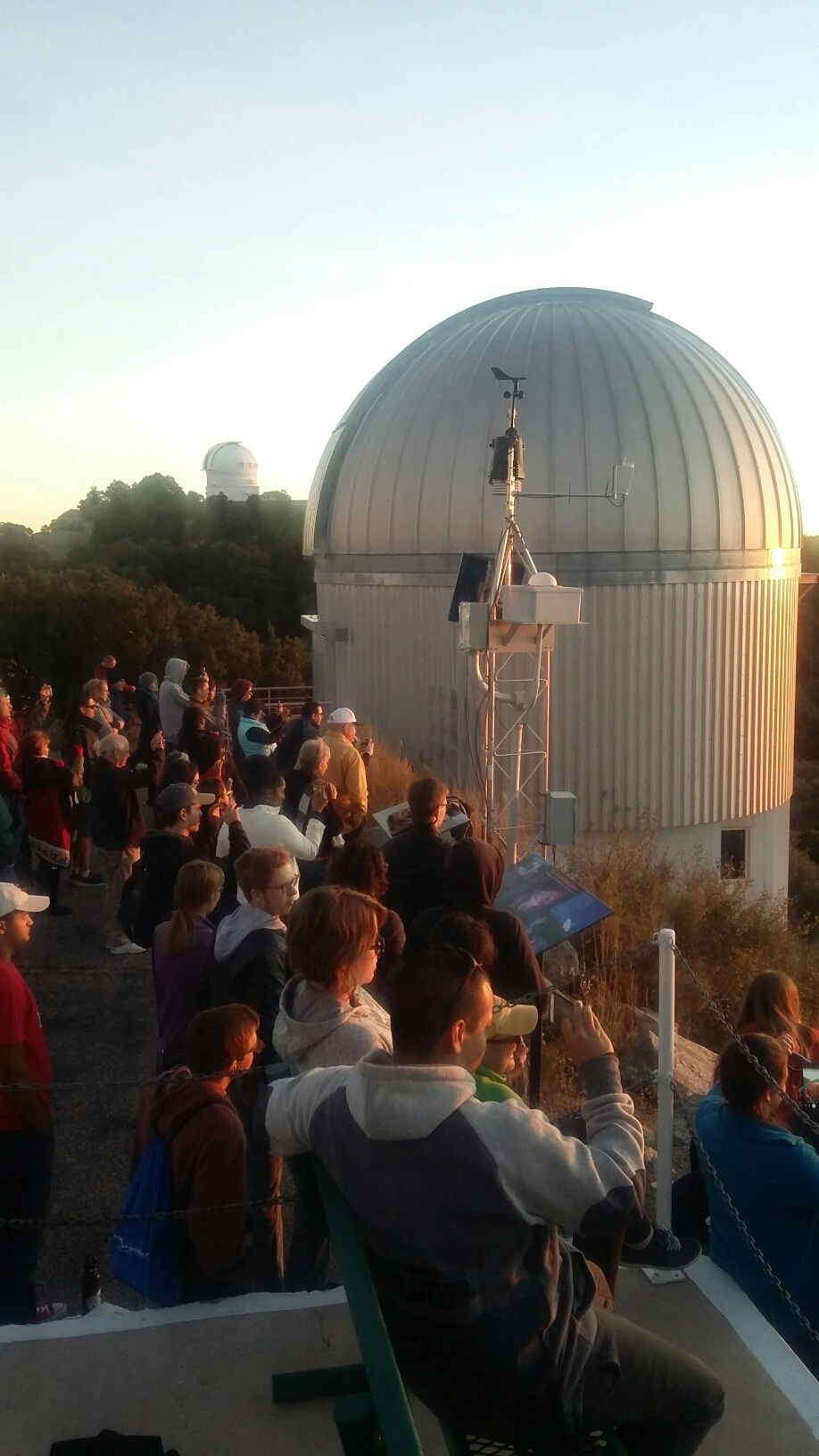 A large group of UA Space Grant Interns, SEDS and Astronomy Club members watch sunset at Kitt Peak Observatory, with telescopes in background.