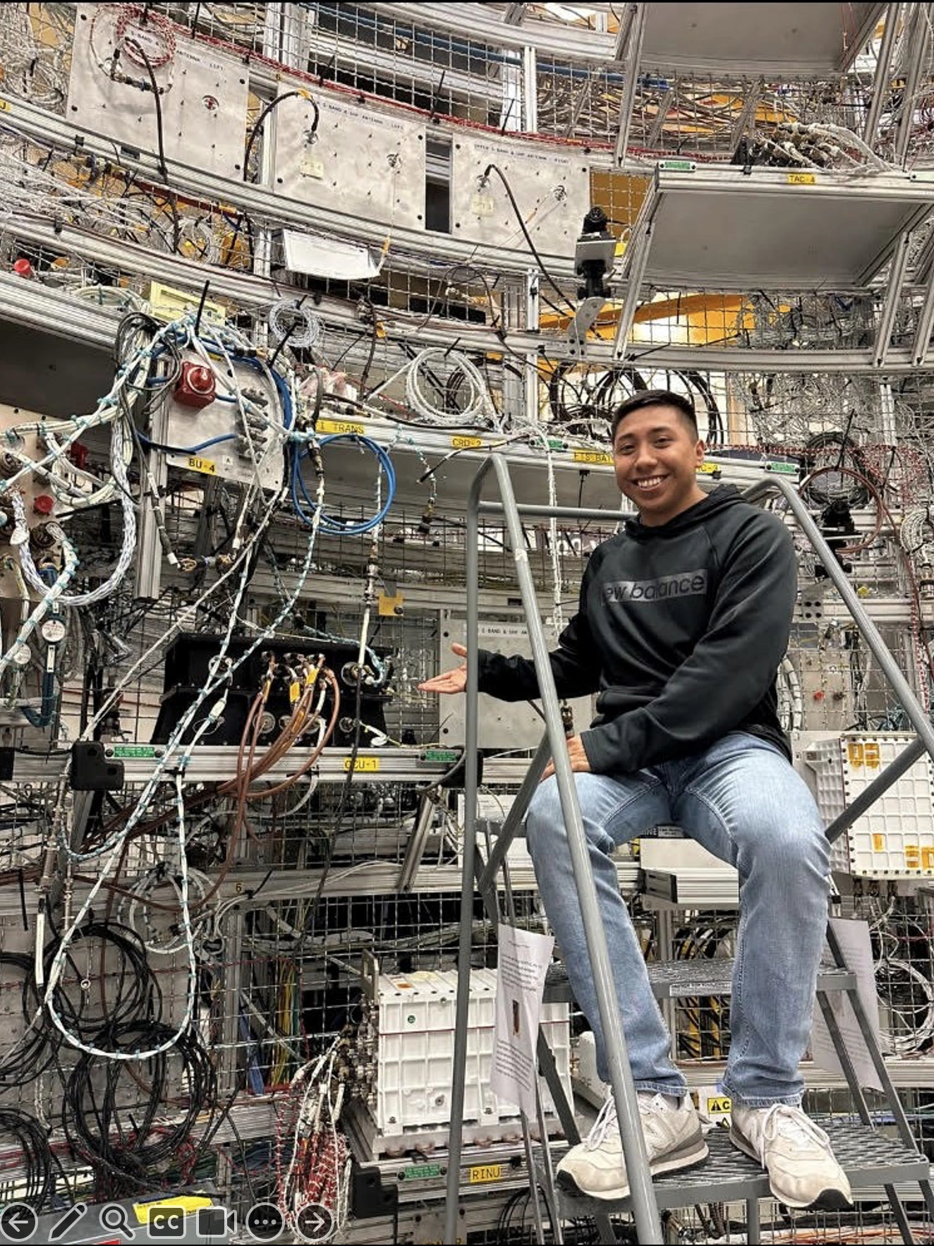 David Ordaz Perez in the lab at Marshall Spaceflight Center. David stands on a latter next to all of the lab equipment.